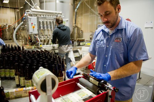 Scott Tubiak hand rolls labels onto beer bottles at Jekyll Brewing in Alpharetta on Tuesday, February 18, 2014. 