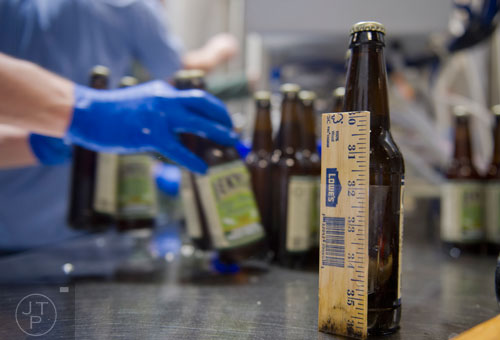 A ruler sits taped to a filled bottle that helps to measure the correct amount of beer during bottling day at Jekyll Brewing in Atlanta on Tuesday, February 18, 2014.