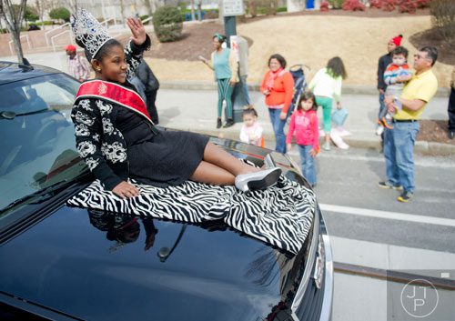 Auryanna Bellard (left) waves to the crowd as she rides on the hood of an SUV down Auburn Ave. in Atlanta during the Black History Month Parade on Saturday, February 22, 2014. 