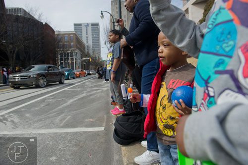 Aaron Butler (center) watches as a group of cars make their way down Auburn Ave. in Atlanta during the Black History Month Parade on Saturday, February 22, 2014. 