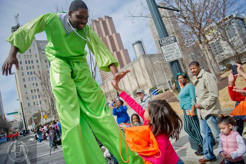 Kenval Thomas (left) walks on a pair of stilts as he reaches down to give a high five to Andrea Sigala during the Black History Month Parade in Atlanta on Saturday, February 22, 2014. 