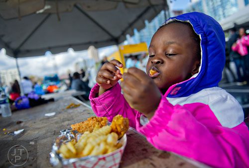 McKenzie Calhoun takes a big bite of chicken fingers during the second annual Atlanta Taste of The Trucks Festival in a parking lot off of Spring and 8th streets in downtown Atlanta on Saturday, March 29, 2014. 