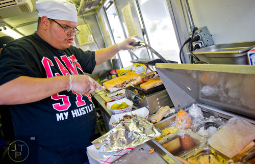 Luis Camacho takes a chicken sandwich off of the sandwich press inside the Buen Provecha food truck during the second annual Atlanta Taste of The Trucks Festival in a parking lot off of Spring and 8th streets in downtown Atlanta on Saturday, March 29, 2014.