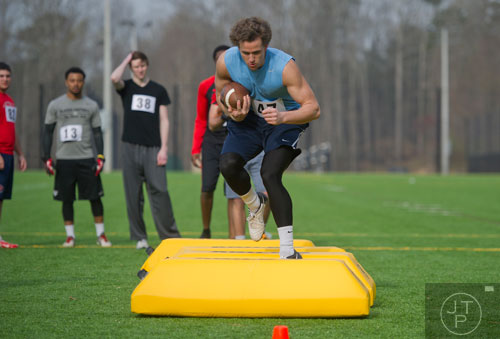 Patrick Jones (center) carries the ball as he high steps over a line of bags in a receiver drill during the first tryouts for the new Kennesaw State University football team at The Perch on campus on Saturday, March 22, 2014. 