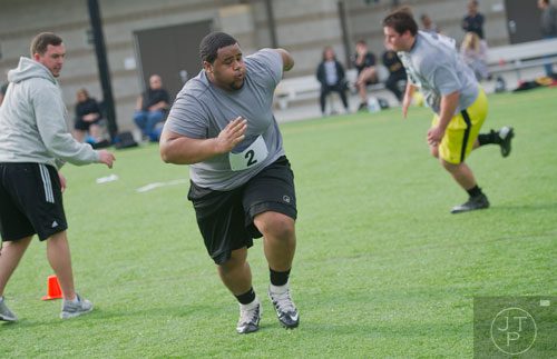 Barry Alvarado (center) and Avery Easton (right) run in a power pull drill during the first tryouts for the new Kennesaw State University football team at The Perch on campus on Saturday, March 22, 2014. 