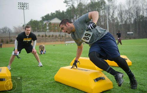 George Thomas (right) cuts hard around a bag as coach Shane Bowen watches in a linebacker drill during the first tryouts for the new Kennesaw State University football team at The Perch on campus on Saturday, March 22, 2014. 
