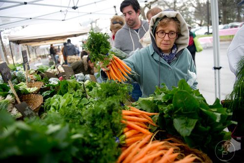 Laura Vaughn (right) picks out a bunch of carrots at the Woodland Gardens booth during the Freedom Farmers Market at the Carter Center in Atlanta on Saturday, March 1, 2014.