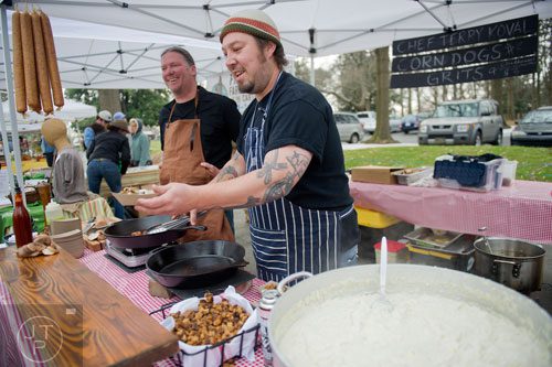 Wrecking Bar chef Terry Koval (center) hands a tasting of grits and corndogs over to a customer as Hudson Rouse helps him during the Freedom Farmers Market at the Carter Center in Atlanta on Saturday, March 1, 2014. 