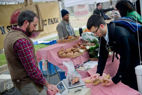 Mitch Lawson (left) rings up Anthony Damelio at the Rise 'N Shine Organic Farm booth during the Freedom Farmers Market at the Carter Center in Atlanta on Saturday, March 1, 2014. 