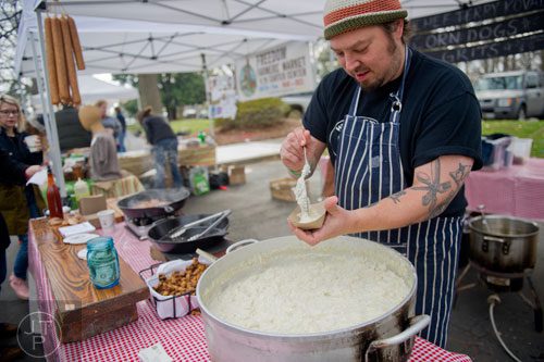 Wrecking Bar chef Terry Koval (center) scoops grits and corndogs into a bowl during the Freedom Farmers Market at the Carter Center in Atlanta on Saturday, March 1, 2014. 