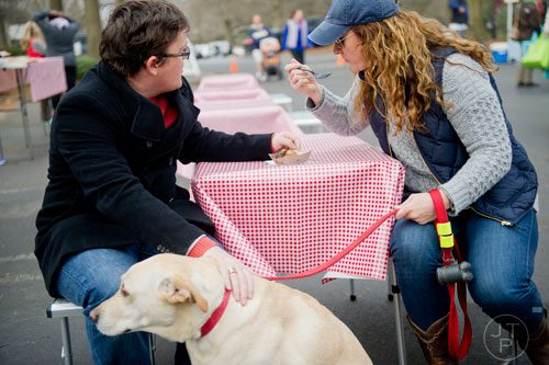 David Ratajczak (left) shares a plate of food with his wife Allison as he pets his dog Mister Bones during the Freedom Farmers Market at the Carter Center in Atlanta on Saturday, March 1, 2014. 