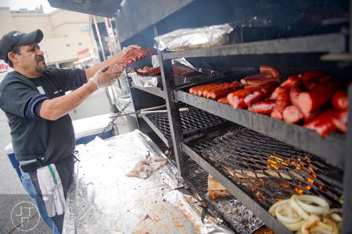 Juan Mendez checks on his ribs and sausage during the Beer, Bourbon & BBQ Festival at Atlantic Station in Atlanta on Saturday, March 1, 2014. 