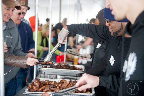 D.J. Whitty (right) dishes out a plate of flavored bacon during the Beer, Bourbon & BBQ Festival at Atlantic Station in Atlanta on Saturday, March 1, 2014.