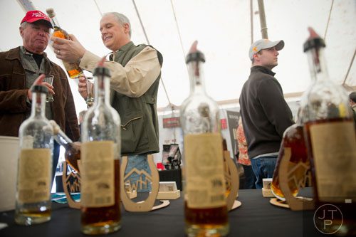 Chris Cykoski (center) shows his father Dave a bottle of bourbon during the Beer, Bourbon & BBQ Festival at Atlantic Station in Atlanta on Saturday, March 1, 2014. 