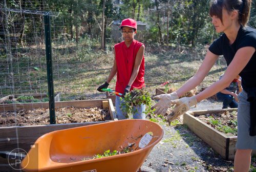 Isaiah Jones (left) and Kat Roberts pile dead leaves and weeds into a wheel barrow at the Cator Woolford Gardens at the Frazer Center in Atlanta on Sunday, March 2, 2014. 