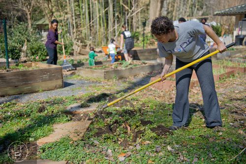 Amy Price (right) uses a hoe to remove weeds from one of the garden beds at the Cator Woolford Gardens at the Frazer Center in Atlanta as she leads a group of volunteers on Sunday, March 2, 2014. 