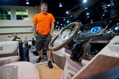 Marty Rabun climbs aboard one of the pontoon boats on display during the Spring Into Summer Boat Show at the Gwinnett Center in Duluth on Sunday, March 9, 2014.