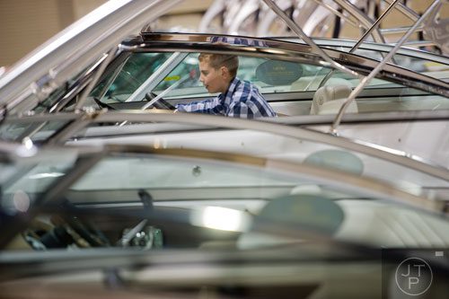 Ben Fisher sits behind the wheel of one of the boats on display during the Spring Into Summer Boat Show at the Gwinnett Center in Duluth on Sunday, March 9, 2014.