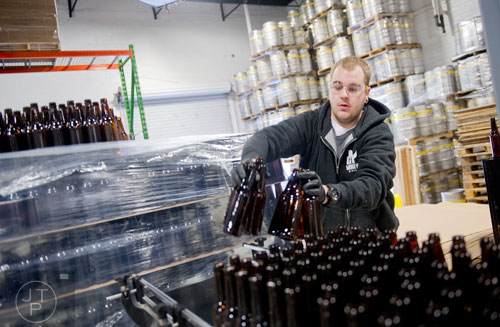 Rhett Caseman places empty beer bottles on the conveyor belt leading to the bottling machine at Monday Night Brewing in Atlanta on Tuesday, February 18, 2014.
