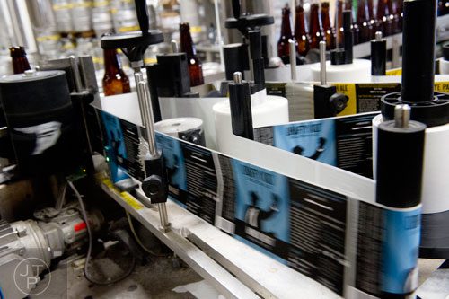 Labels are applied to beer bottles as they circulate through the bottling machine at Monday Night Brewing in Atlanta on Tuesday, February 18, 2014.