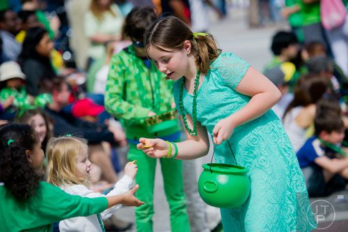 Phoebe Sercer (right) hands out golden coins from her green pot during the Atlanta St. Patrick's Day Parade on Saturday, March 15, 2014. 