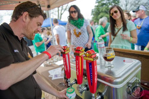Nick Purdy (left) pours glasses of beer for Alicia Losli and Carly Ward during the Roswell Beer Festival & Cornhole Tournament at historic Roswell square on Saturday, March 15, 2014. 