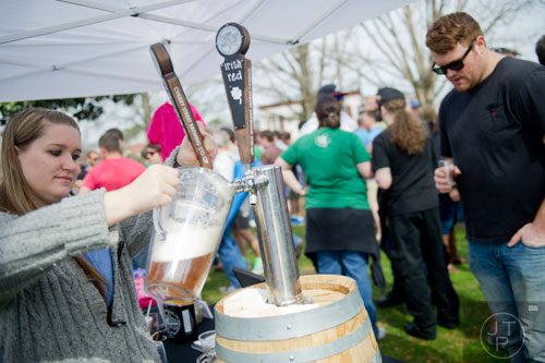 Alisa Tanner (left) pours a pitcher of beer from a keg during the Roswell Beer Festival & Cornhole Tournament at historic Roswell square on Saturday, March 15, 2014. 
