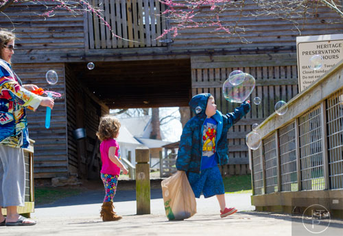 Ethan Rollins (right) and his sister Abigail chase after a bubbles blown by their mother Kristina at McDaniel Farm Park in Duluth on Thursday, March 20, 2014. 