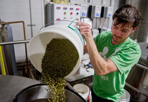 Adam Bishop pours hops into a kettle of beer as he brews at Monday Night Brewing in Atlanta on Thursday, February 20, 2014.