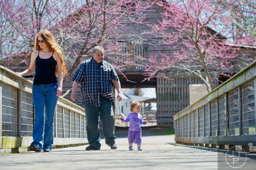 Amanda Padavano (left) and Sam Juarez lead their daughter Hannah across the bridge at McDaniel Farm Park in Duluth on Thursday, March 20, 2014. 