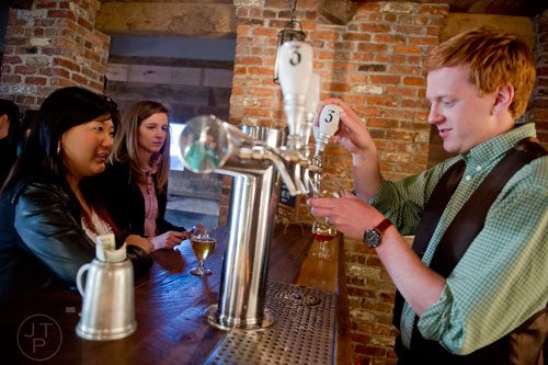 Danny Ritchie (right) pours a beer for Hannah Cho (left) and Natalie Rogol at Three Taverns Craft Brewery in Decatur on Friday, February 21, 2014. 