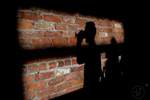 A shadow of someone drinking at Three Taverns Craft Brewery in Decatur is reflected on the brick wall on Friday, February 21, 2014.