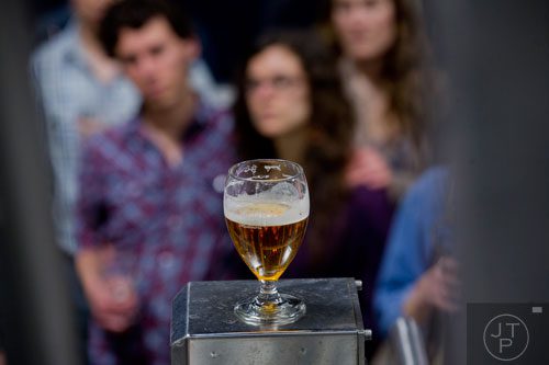 A glass of beer sits in front of a crowd of people as they take a tour of Three Taverns Craft Brewery in Decatur on Friday, February 21, 2014.