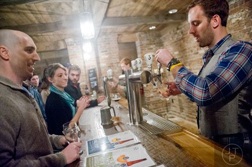 J.V. Gortney (right) pours a beer for Jeff Burnett as Julia Interrante waits her turn to order at Three Taverns Craft Brewery in Decatur on Friday, February 21, 2014. 