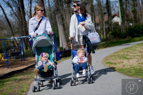 Kyndal Braly (left) pushes her daughter Malone in a stroller as she walks and talks with Mandy Brien who also pushes her son Campbell in a stroller at Glenlake Park in Decatur on Friday, March 21, 2014. 