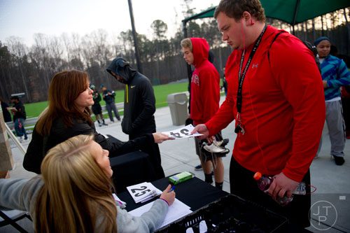 Kate Singer (left) hands Brett Gillespie his number during the first tryouts for the new Kennesaw State University football team at The Perch on campus on Saturday, March 22, 2014. 