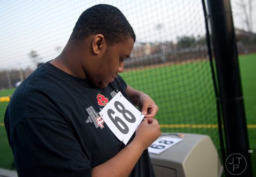 Darice Parks pins his number to his shirt during the first tryouts for the new Kennesaw State University football team at The Perch on campus on Saturday, March 22, 2014.