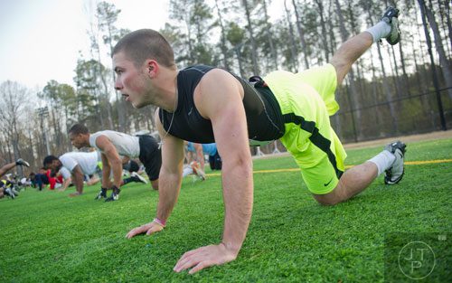 Austin Franzen lifts his legs into the air for stretching drills during the first tryouts for the new Kennesaw State University football team at The Perch on campus on Saturday, March 22, 2014. 