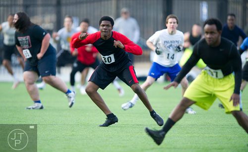 Patrick Ehui (center) runs through stretching drills during the first tryouts for the new Kennesaw State University football team at The Perch on campus on Saturday, March 22, 2014.