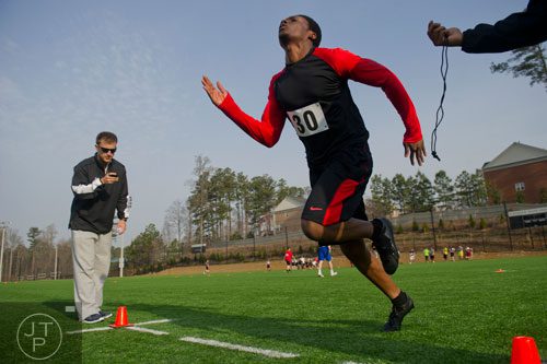 Patrick Ehui (center) stretches to cross the finish line for a 40 meter dash as coach Cody Worley checks the time on his stopwatch during the first tryouts for the new Kennesaw State University football team at The Perch on campus on Saturday, March 22, 2014. 