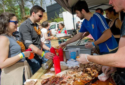 Shelbi Bailey (left) and Barend Havenga wait in line for some pork as Anthony DeStefano fills their plates with food during the Hogs and Hops festival at the Masquerade in Atlanta on Saturday, April 5, 2014. 