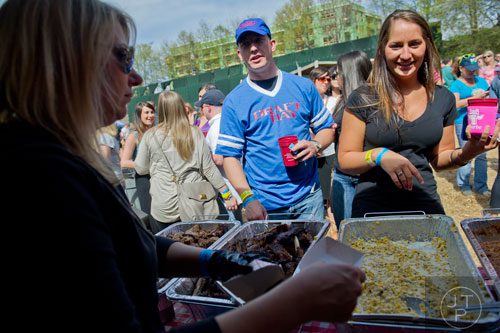 Marissa Selementi (right) and Thomas Gallagher stand in line as Brandice Thorn scoops barbeque onto plates during the Hogs and Hops festival at the Masquerade in Atlanta on Saturday, April 5, 2014. 