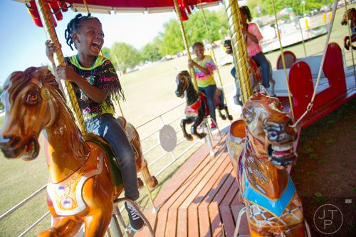 Naila Drummond (left) rides the merry-go-round, one of numerous carnival rides available during the 78th Annual Atlanta Dogwood Festival at Piedmont Park on Saturday, April 12, 2014.