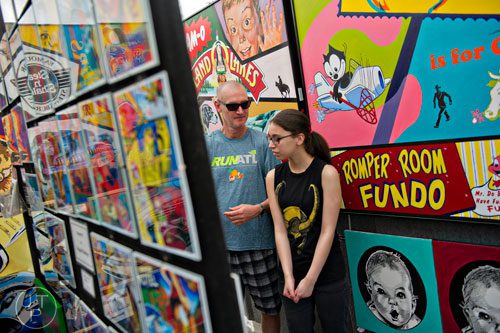 Marissa Davis (right) and her father Carl look at the artwork on display in Brian J. Sullivan's booth during the 78th Annual Atlanta Dogwood Festival at Piedmont Park on Saturday, April 12, 2014. 