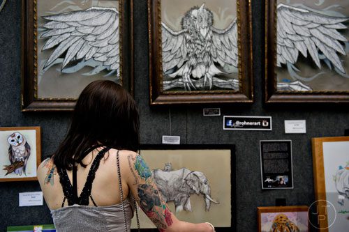 Metala Theart looks at the artwork on display in Michael Rohner's booth during the 78th Annual Atlanta Dogwood Festival at Piedmont Park on Saturday, April 12, 2014. 