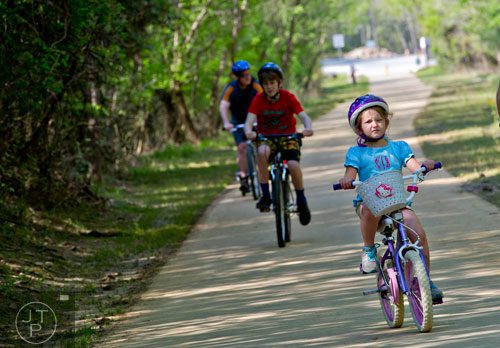 Bridson Jones (right), her brother Bennett and father Steve ride their bikes down the path of the Big Creek Greenway in Alpharetta on Saturday, April 12, 2014. 