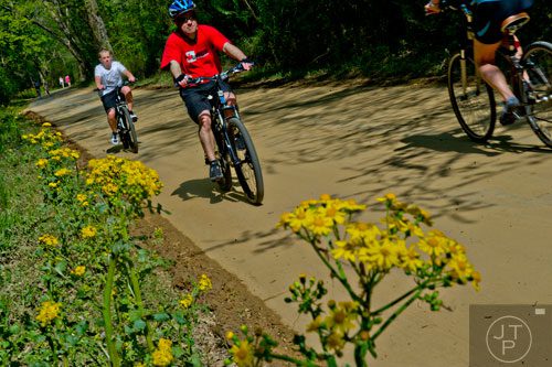 Jean-Francois Moneyron (center) and his son Sebastien ride their bikes down the path of the Big Creek Greenway in Alpharetta on Saturday, April 12, 2014.