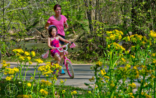 Grace Lochman (front) rides her bike as her mother Nancy runs next to her down the path of the Big Creek Greenway in Alpharetta on Saturday, April 12, 2014.  