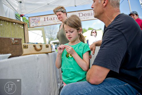 Tessa Sander (center) looks at a necklace with her father Karl as they check out the jewelry in Courtney Loving's booth during the Sandy Springs Artsapalooza on Sunday, April 13, 2014. 
