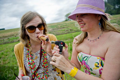 Kylie James (left) has her cigar lit by Cassia Adams during the 49th Annual Running of the Atlanta Steeplechase At Kingston Downs in Rome on Saturday, April 19, 2014. 